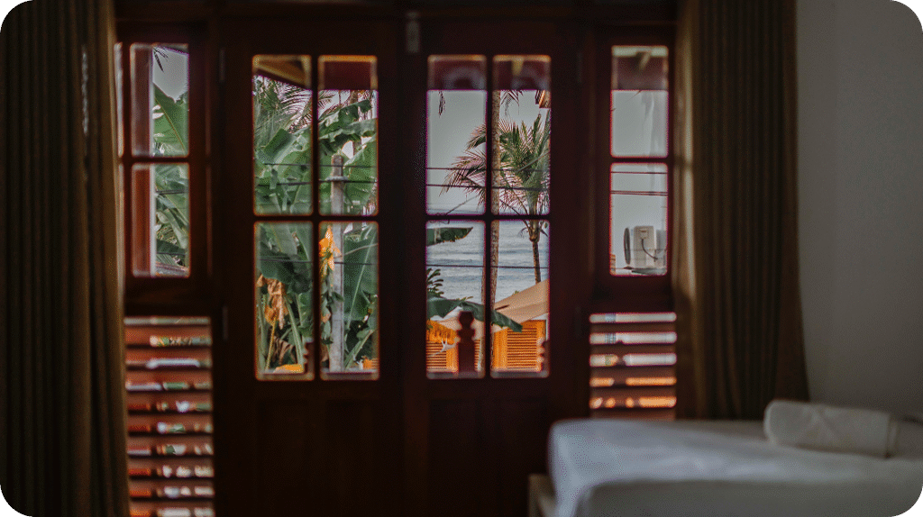 Tailslide boutique surf house_Sea view room interior with ocean view balcony through wooden windows_boutique quality aircon surf accommodation Madiha Sri Lanka_SurfHouse
