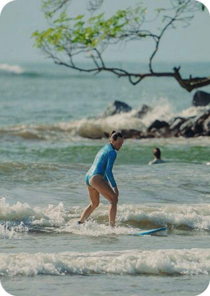 Beginner surfer particing to stand up on white water at the Island in Weligama beach — part of Tailslide Surf House’s technical surf coaching lessons.